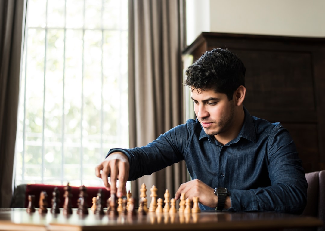 Échecs — man in blue dress shirt sitting down and playing chess game